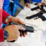 Person holding and inspecting a handgun at display.