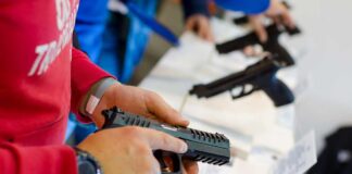 Person holding and inspecting a handgun at display.