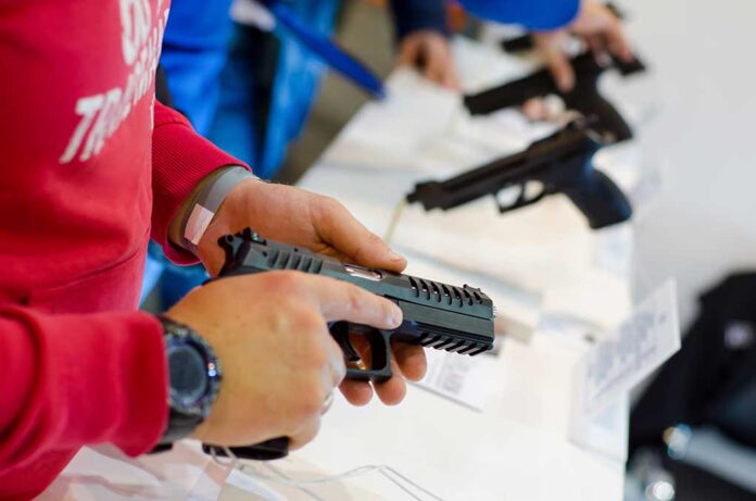 Person holding and inspecting a handgun at display.