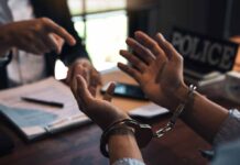 Person in handcuffs being interrogated at a desk.