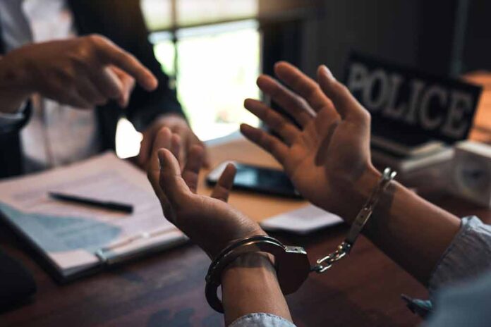 Person in handcuffs being interrogated at a desk.