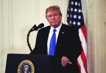 Donald Trump speaking at a podium with American flag.