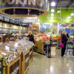 People shopping in a grocery store produce section.