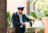 Mail carrier placing envelope in a residential mailbox.