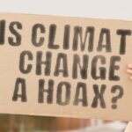 Person holding sign: "IS CLIMATE CHANGE A HOAX?"