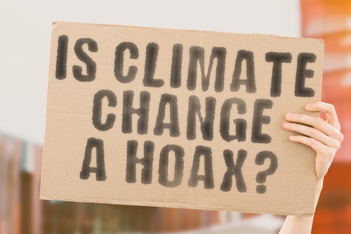 Person holding sign: "IS CLIMATE CHANGE A HOAX?"