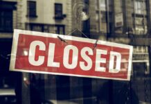 Red closed sign hanging in a window.