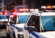 Police cars with flashing lights in an urban setting.