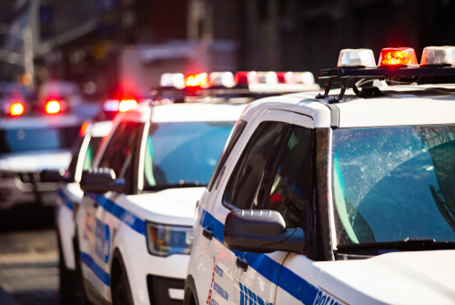 Police cars with flashing lights in an urban setting.