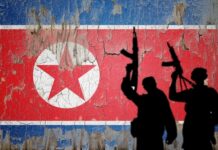 Silhouetted soldiers in front of North Korean flag.