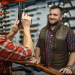 Two men examining a handgun in a gun shop.