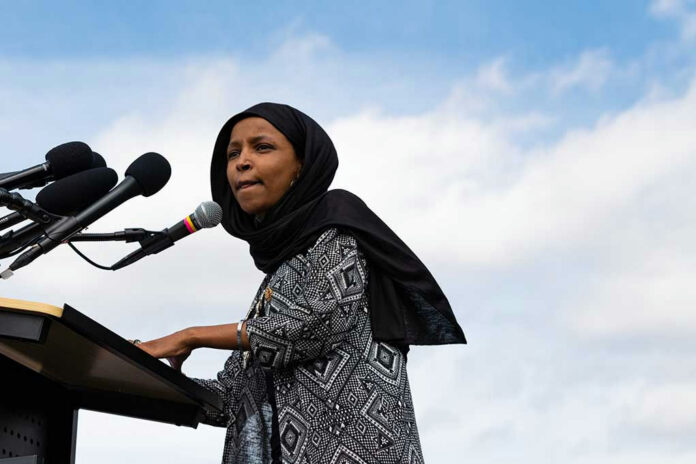 1341075257 Woman in hijab speaking at podium with microphones.