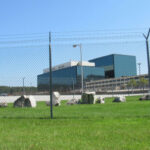 Chain-link fence in front of a large modern office complex