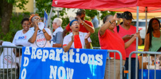 Protesters holding Reparations NOW banner at rally.