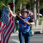 Person carrying a large American flag during a street demonstration