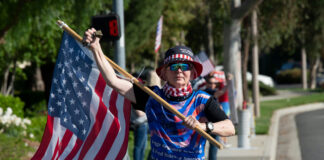 Person carrying a large American flag during a street demonstration