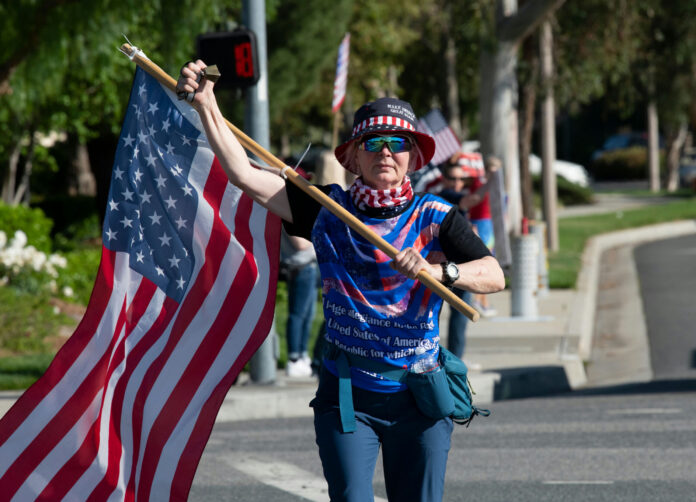 shutterstock2422207721jpg Person carrying a large American flag during a street demonstration