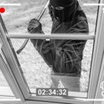 Security camera footage showing masked burglar breaking window.