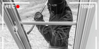 Security camera footage showing masked burglar breaking window.