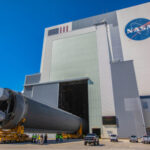Blue Origin’s Engine BLAST: Hidden Risks Exposed A large rocket being transported outside a NASA building under a blue sky