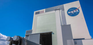 A large rocket being transported outside a NASA building under a blue sky
