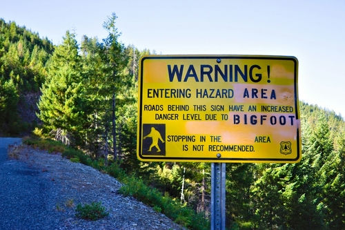shutterstock_2092911811.jpg Warning sign about Bigfoot in forested area.