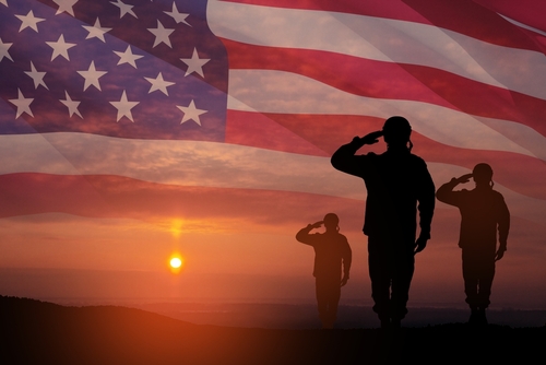 Silhouettes,Of,Soldiers,Saluting,On,Background,Of,Sunset,Or,Sunrise Silhouetted soldiers saluting against an American flag backdrop during sunset