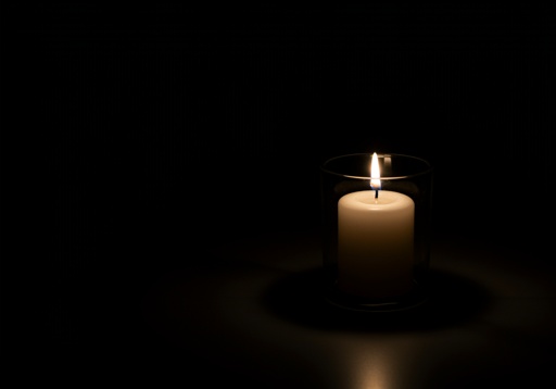 shutterstock_2617544113.jpg A lit candle in a glass holder against a dark background