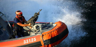 Person on orange boat holding machine gun.
