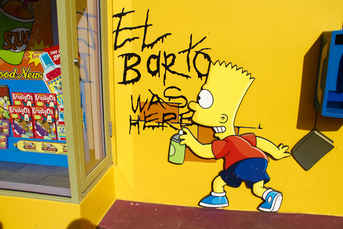 Graffiti of Bart Simpson writing El Barto was here on a yellow wall