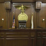 Colorado Uproar: Convicted Clerk Walks Free Judges bench in an empty courtroom, scales emblem above.