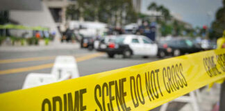 Yellow Crime Scene Do Not Cross tape across street.