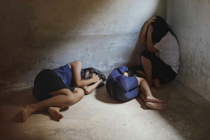 Three people huddled in a dimly lit corner.