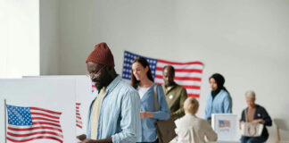 People voting in a polling station with American flags.