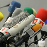 Cluster of various microphones at a press conference.