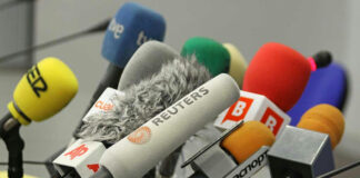Cluster of various microphones at a press conference.