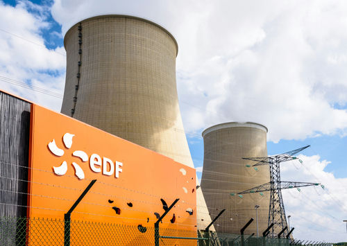 shutterstock1815319076jpg cooling towers at a power plant behind security fence
