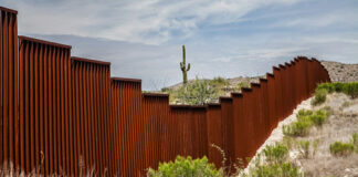 rust-colored border fence in a desert landscape