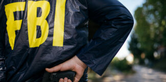 FBI agent holding a gun behind their back.