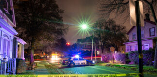 Police car with flashing lights at a crime scene surrounded by caution tape