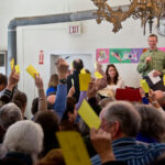 People holding up voting cards at a meeting.