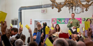 People holding up voting cards at a meeting.