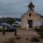 Police vehicles and officers at a crime scene near an abandoned building in a desert area