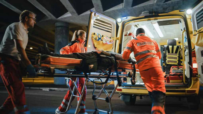 Paramedics loading patient into ambulance at night.