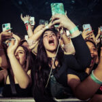 Concert crowd cheering and taking photos with phones.