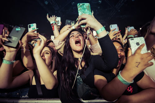 Concert crowd cheering and taking photos with phones.