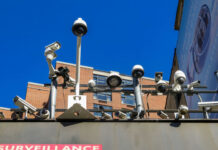 Array of security cameras mounted above a building facade under a clear blue sky
