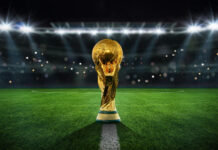 Golden trophy on soccer field under stadium lights