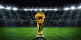 Golden trophy on soccer field under stadium lights