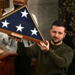 Man holding folded American flag in wooden case.